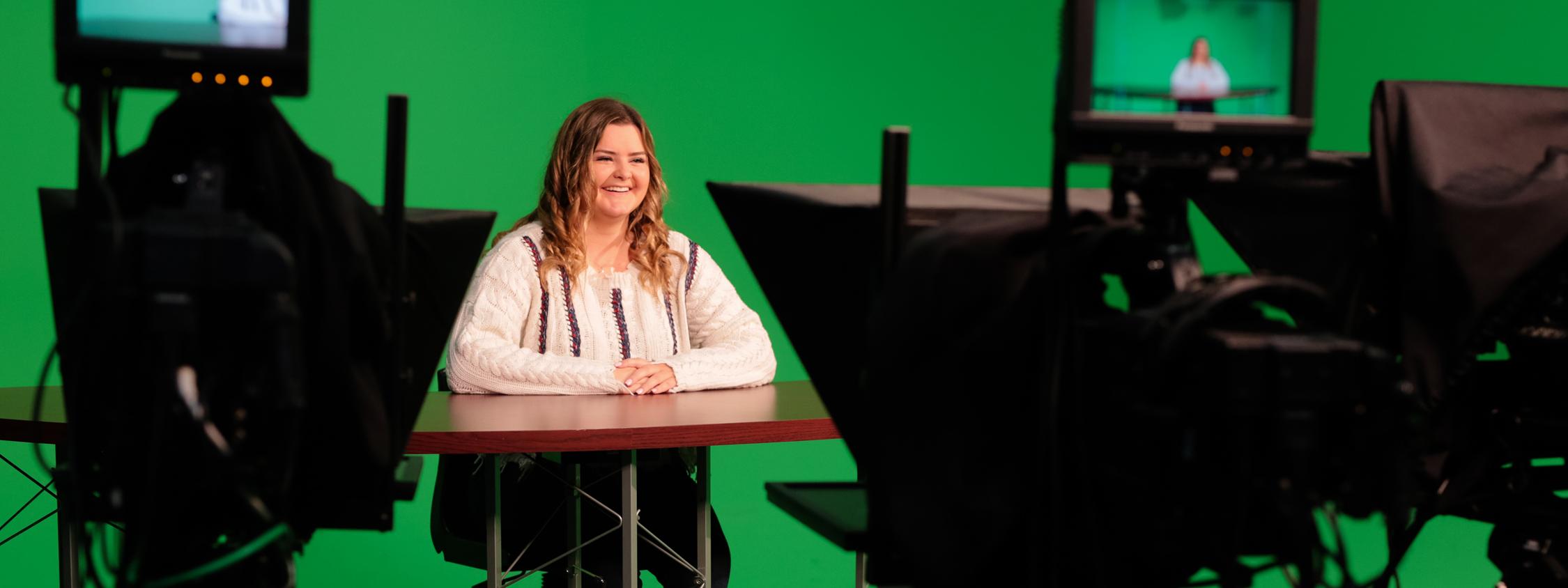 student in front of a green screen